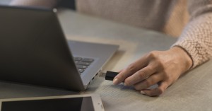 Woman plugging a USB drive into her laptop, technology and data storage concept