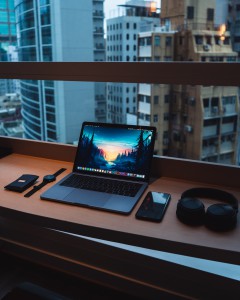 Laptop, watch, phone, headphones on desk. Photo by Austin Poon
